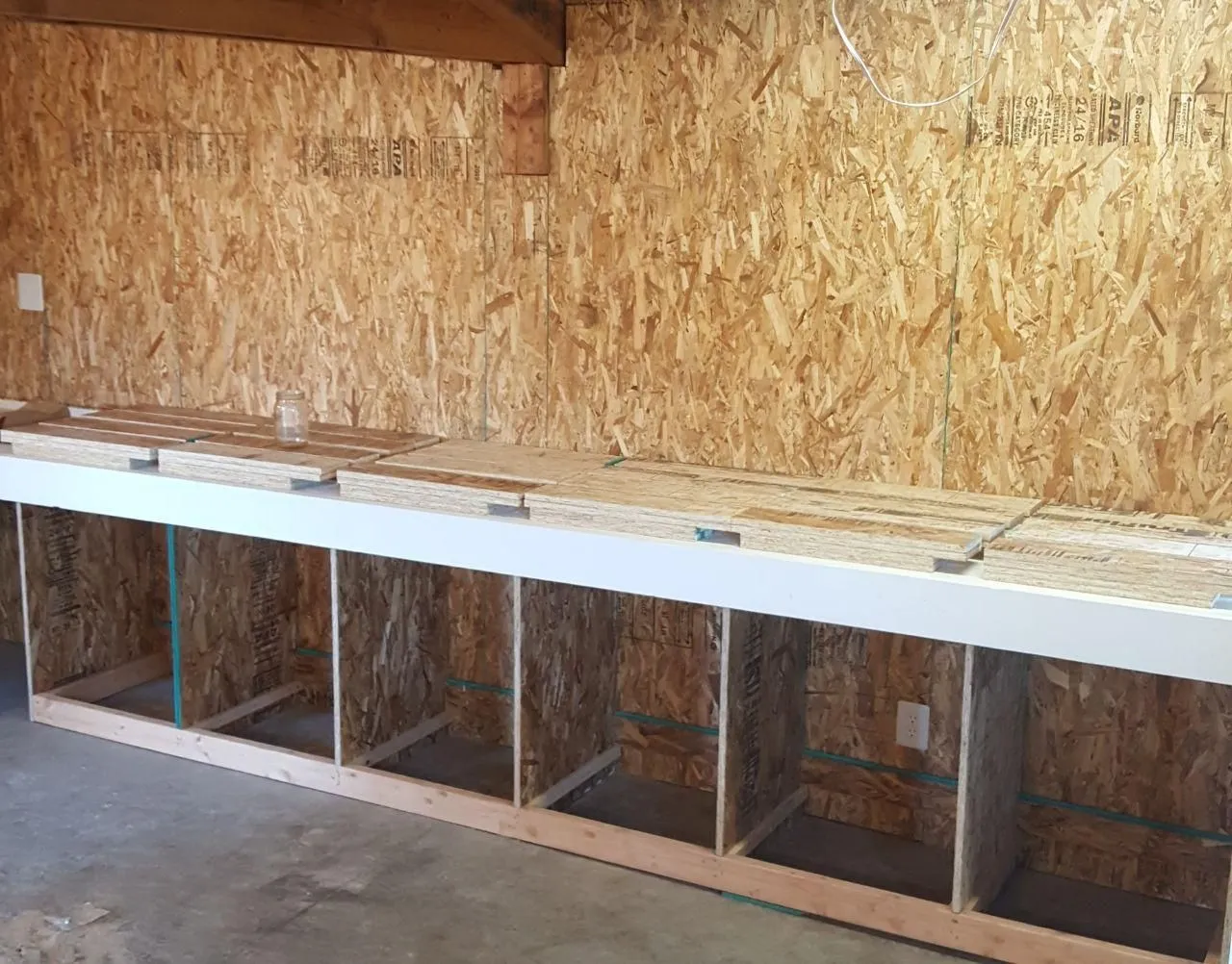 Wooden workbench with open cubbies against a wall with wood paneling.