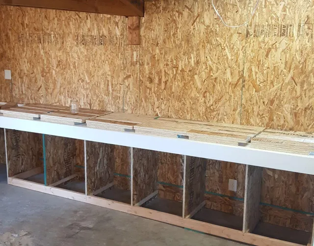 Wooden workbench with open cubbies against a wall with wood paneling.