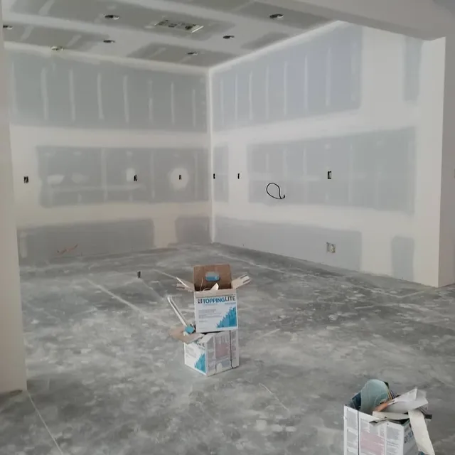 Interior room under construction with drywall installed and boxes on the concrete floor.