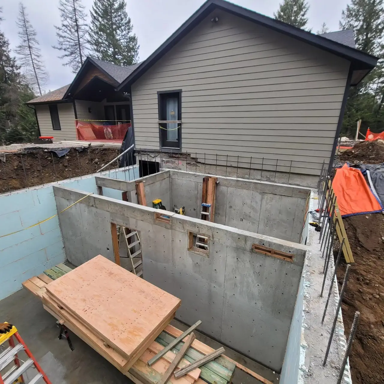 New basement foundation walls with exterior insulation poured next to an existing North Idaho home
