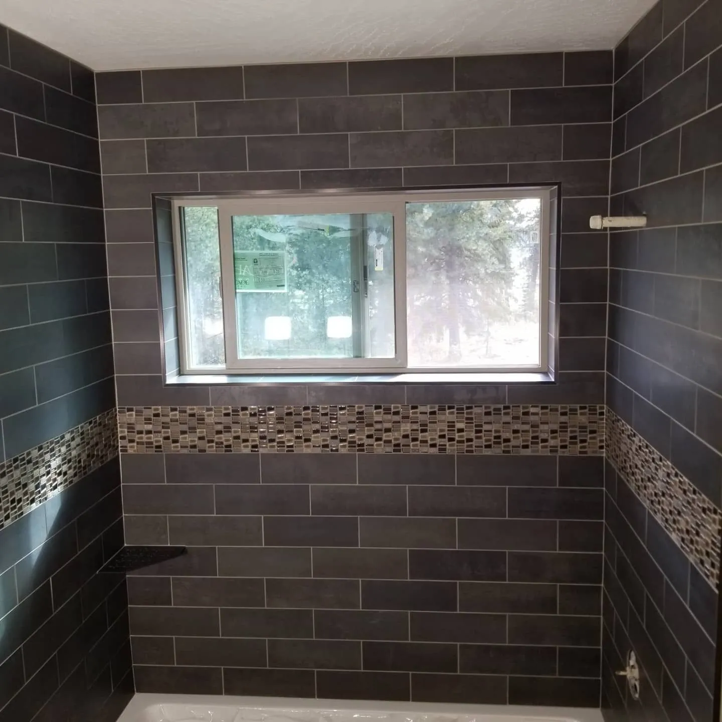 Bathroom with dark gray subway tile walls and a decorative mosaic border.