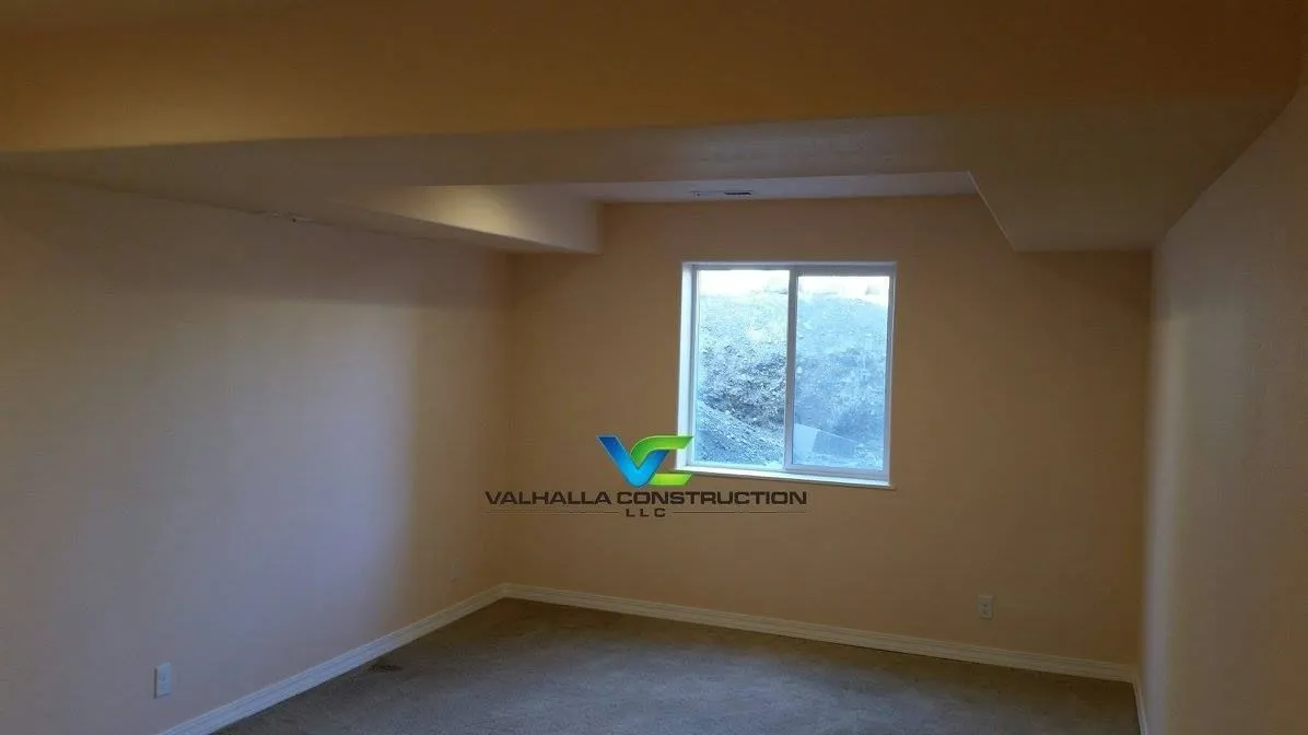 Empty room with a window, beige walls, and a recessed ceiling.