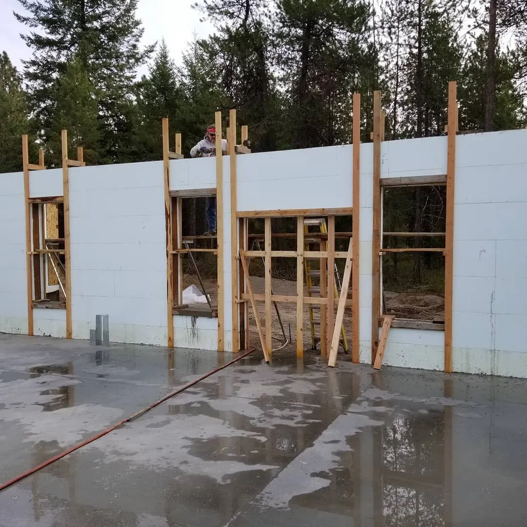 Concrete foundation with insulated concrete form walls, framing for windows. Forest backdrop.
