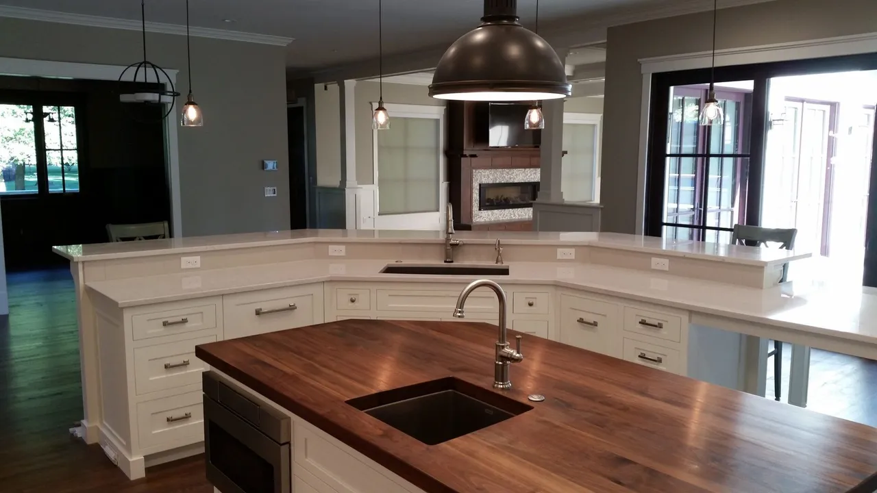 Kitchen with white cabinets, wood island, and pendant lights. A sink sits on the island.