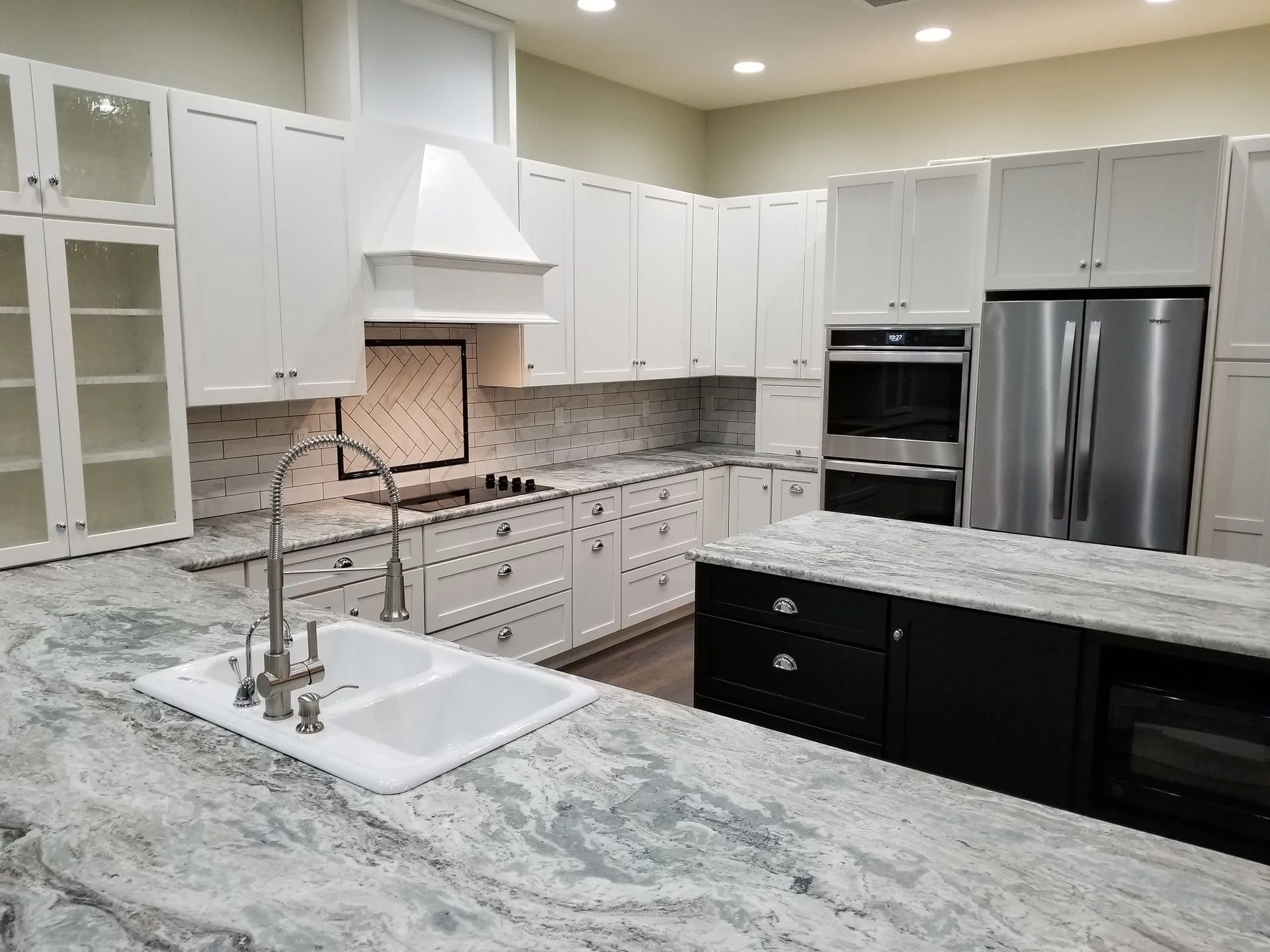 Modern kitchen with white cabinets, stainless steel appliances, and a gray countertop island.