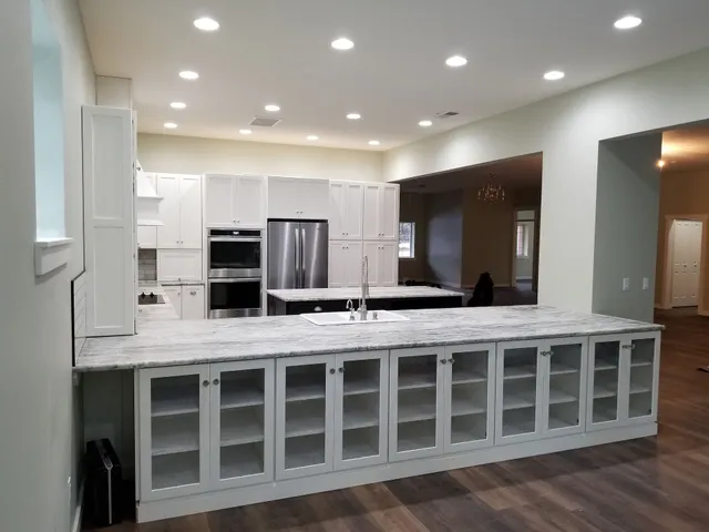 Bright, modern kitchen with white cabinets, stainless steel appliances, and a large countertop island.