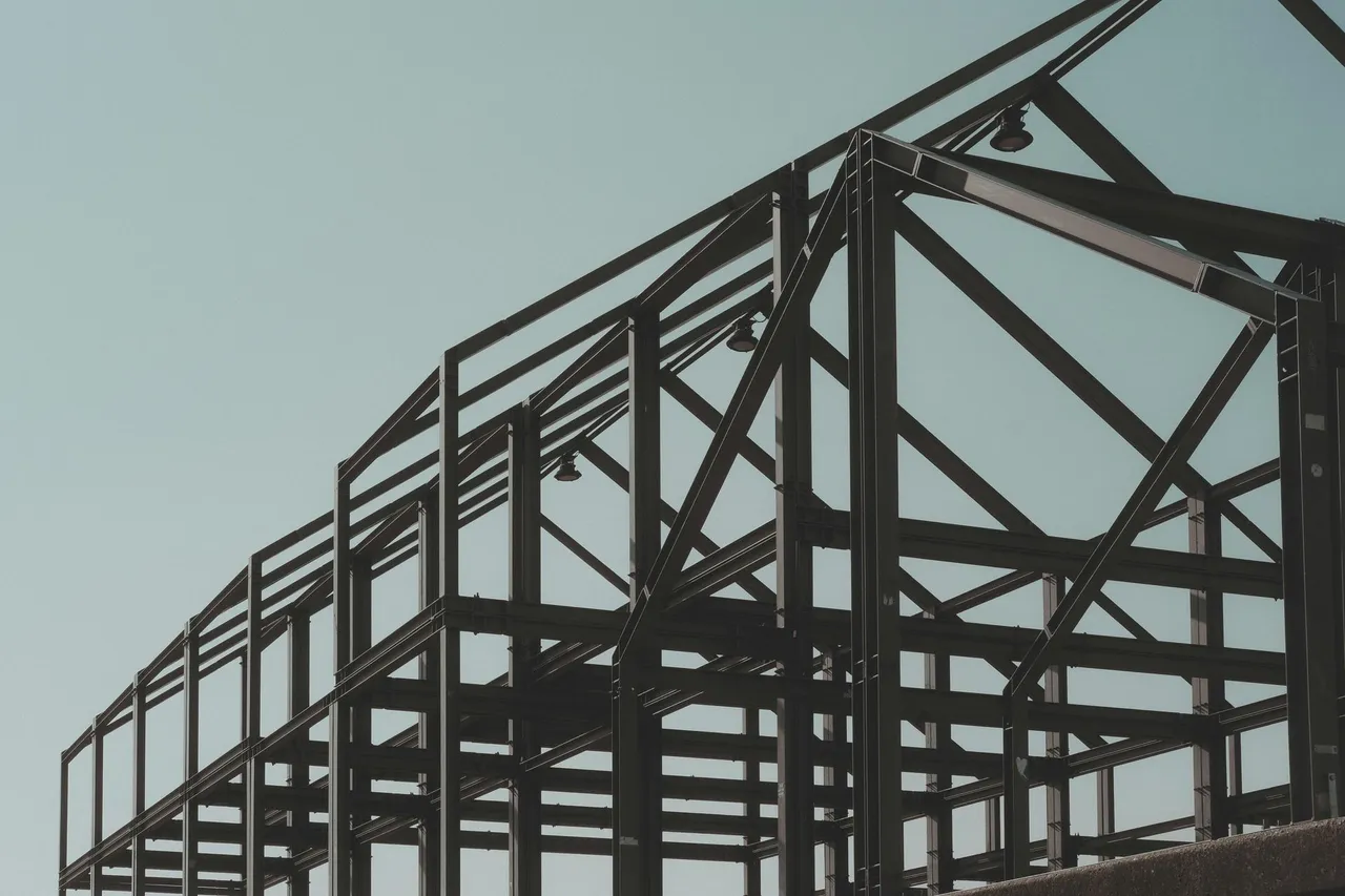 Wooden staircase under construction, with metal spindles. A-frame ladder visible.