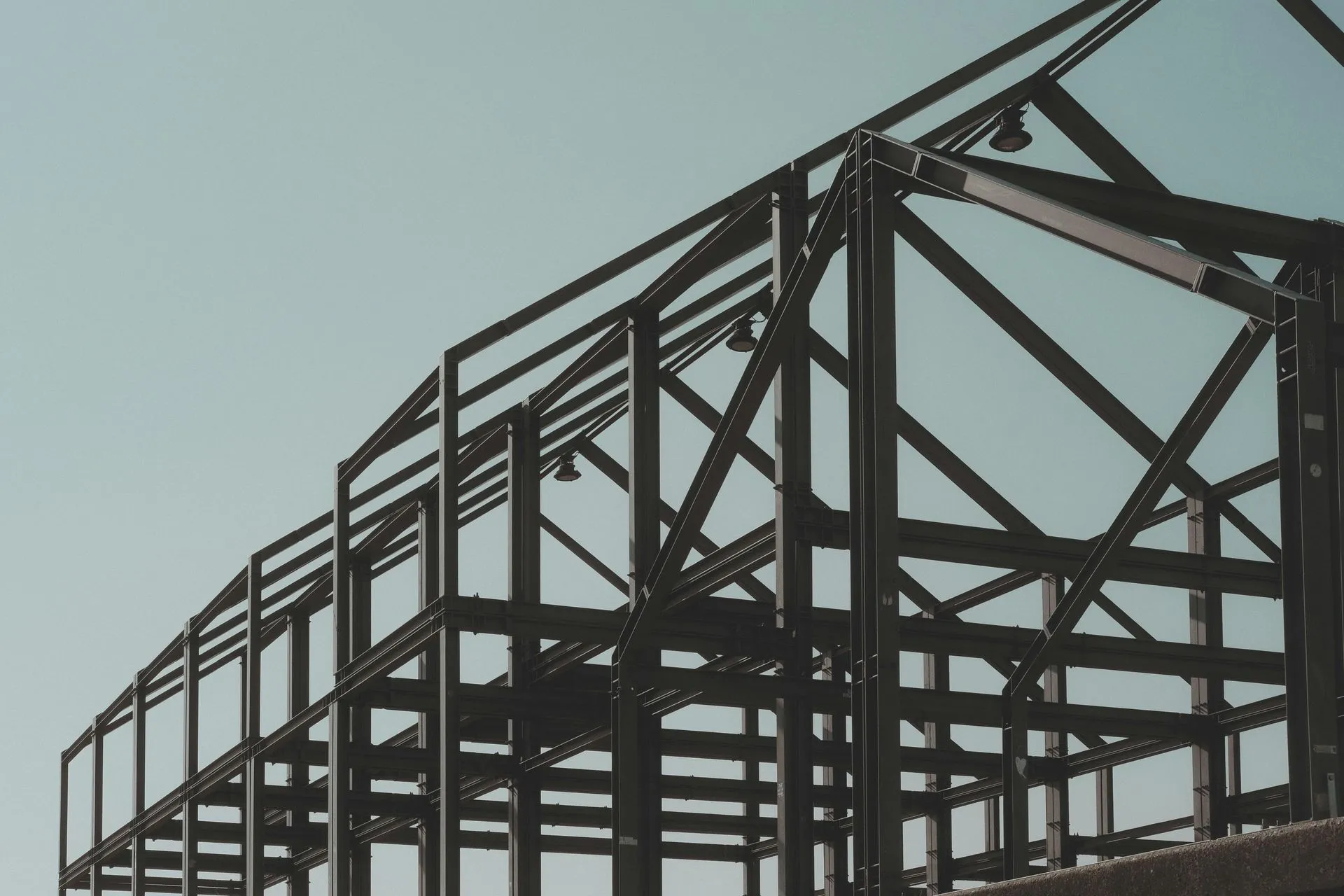Wooden staircase under construction, with metal spindles. A-frame ladder visible.
