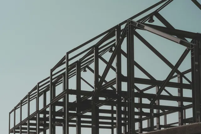 Wooden staircase under construction, with metal spindles. A-frame ladder visible.