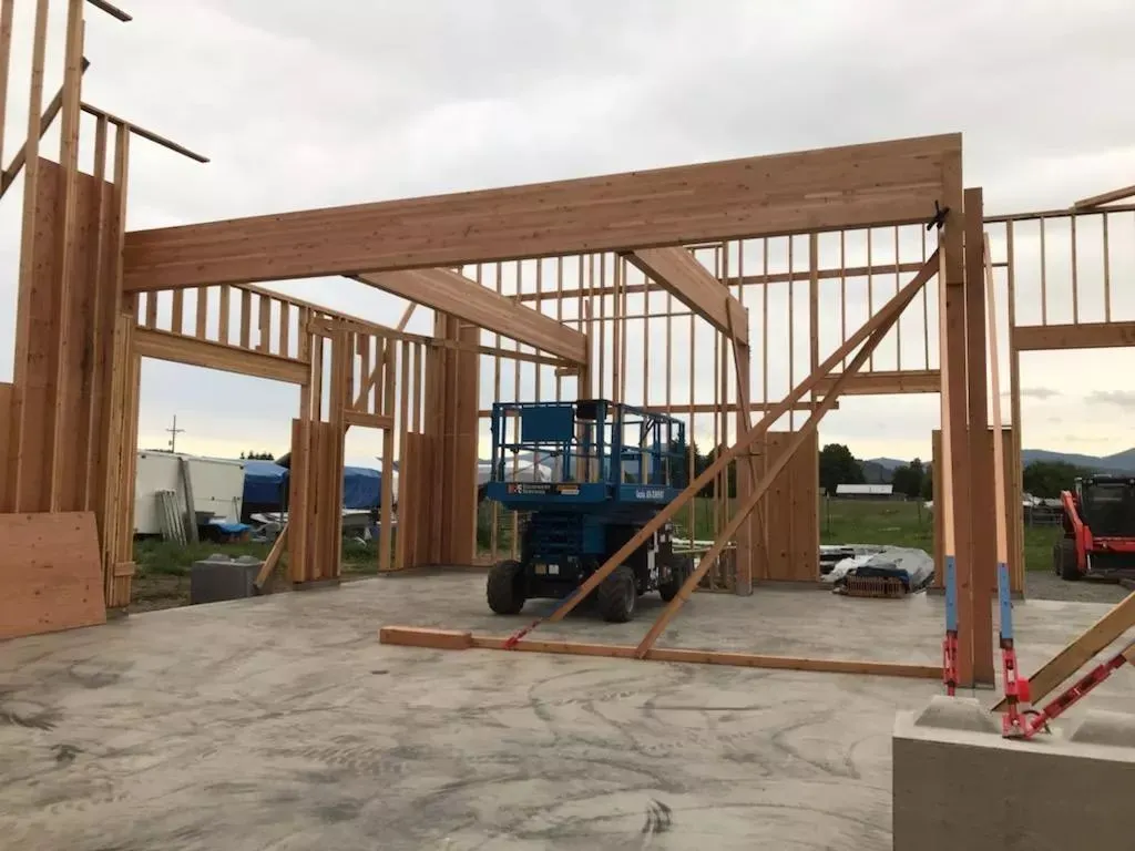 Wood framing of a building under construction, with a lift in the center and overcast sky.