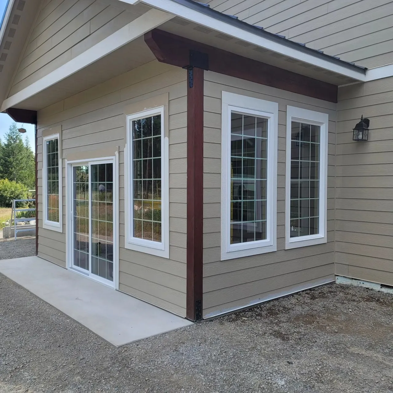 Beige building with white-framed windows, sliding glass door, and a concrete patio.